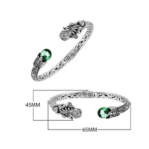 A wholesale sterling silver octopus-themed bangle featuring a bright green quartz stone, ornate Balinese tentacle carvings, oxidized textures, and a secure hinge lock for bulk jewelry orders.