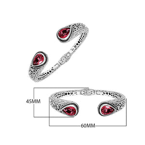 Sterling silver bangle with teardrop red garnet quartz stones, detailed Bali engraving, oxidized texture, and secure hinge lock crafted for wholesale jewelry collections.