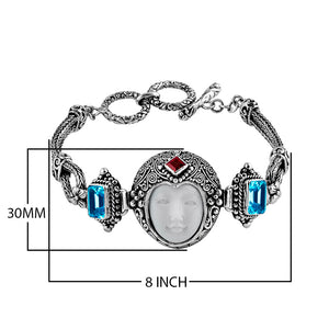 Sterling Silver bracelet featuring a carved bone face centerpiece, Red Garnet Quartz and Blue Topaz Quartz accents, ornate scrollwork, and a secure toggle lock for wholesale collections.