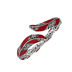 Wholesale sterling silver feather-inspired bangle featuring bold Red Coral inlays, ornate Balinese scroll engravings, and a secure hinge lock for premium artisan-style jewelry assortments.