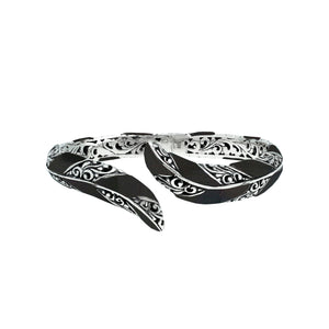 Wholesale sterling silver feather-inspired bangle featuring bold Black Shell inlays, ornate Balinese scroll engraving, and a secure hinge lock for premium artisan-inspired jewelry collections.