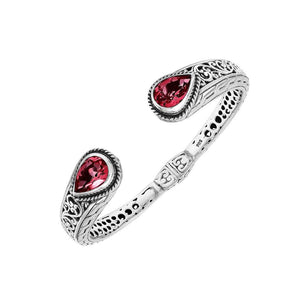 Sterling silver bangle with teardrop red garnet quartz stones, detailed Bali engraving, oxidized texture, and secure hinge lock crafted for wholesale jewelry collections.