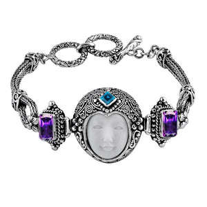 Sterling Silver bracelet featuring a carved bone face centerpiece, Garnet Quartz and Blue Topaz Quartz stones, detailed scroll panels, and a secure toggle lock for wholesale assortments.