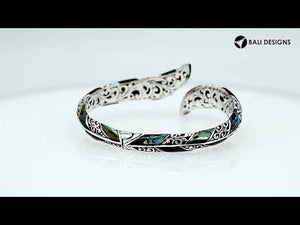 Wholesale sterling silver feather-inspired bangle featuring iridescent Abalone Shell inlays, ornate Balinese scroll engravings, and a secure hinge lock for premium artisan-style jewelry collections.