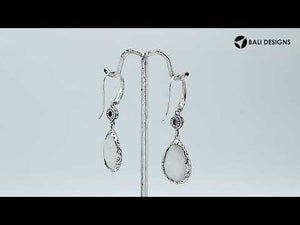 Wholesale sterling silver earrings combining a faceted rainbow moonstone teardrop with an amethyst quartz accent, framed by ornate Balinese detailing for consistent artisan quality and strong catalog-ready wholesale presentation.
