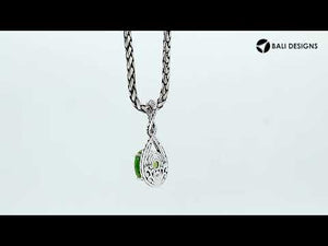 Sterling silver twisted loop pendant featuring a round Peridot Quartz centerpiece with carved Balinese engraving and polished artistic round design.