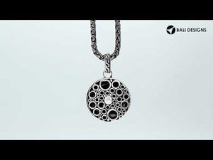 Sterling silver round skull pendant with carved texture and polished detailing.