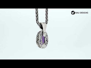 Sterling silver oval pendant featuring faceted Ruby Quartz and detailed Balinese floral engraving.