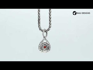 Sterling silver twisted loop pendant featuring a round faceted Red Garnet Quartz centerpiece with carved Balinese detailing and polished artistic round setting.