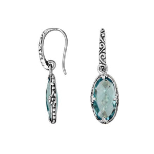 A handcrafted pair of 925 sterling silver earrings featuring faceted oval Blue Topaz Quartz stones with detailed Balinese floral motifs and secure earwire hook design.