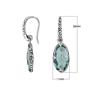 A handcrafted pair of 925 sterling silver earrings featuring faceted oval Blue Topaz Quartz stones with detailed Balinese floral motifs and secure earwire hook design.