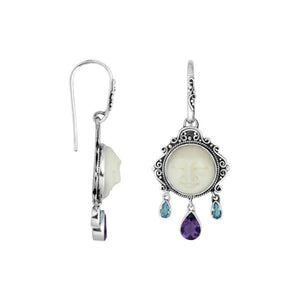 Wholesale sterling silver earrings featuring a carved bone face framed by ornate Balinese detailing, accented with blue topaz quartz and an amethyst quartz drop for consistent artisan-quality presentation.