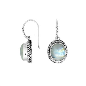 Wholesale sterling silver earrings featuring an oval Rainbow Moonstone cabochon framed with intricate carved detailing and earwire lock, offering luminous sheen and artisan craftsmanship suitable for premium wholesale jewelry catalogs.