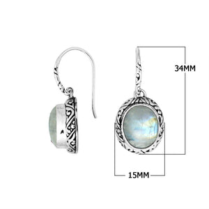 Wholesale sterling silver earrings featuring an oval Rainbow Moonstone cabochon framed with intricate carved detailing and earwire lock, offering luminous sheen and artisan craftsmanship suitable for premium wholesale jewelry catalogs.