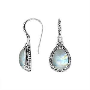 Wholesale sterling silver earrings featuring a softly glowing Rainbow Moonstone teardrop framed with sculpted ornate borders and secured with an earwire lock, ideal for serene, luminous, artisan-inspired wholesale presentations.