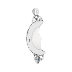 Sterling silver crescent moon pendant with carved bone face and marquise blue topaz gemstone, Balinese artisan jewelry.