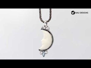Sterling silver crescent moon pendant with carved bone face and marquise blue topaz gemstone, Balinese artisan jewelry.