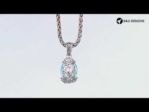 A handcrafted sterling silver pendant featuring a radiant Blue Topaz Quartz in an oval filigree design, reflecting classic Balinese artistry and polished detailing.