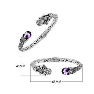 A wholesale sterling silver octopus-inspired bangle featuring a vivid amethyst quartz stone, intricate Balinese carvings, oxidized detailing, and a secure hinge lock mechanism ideal for bulk jewelry buying.