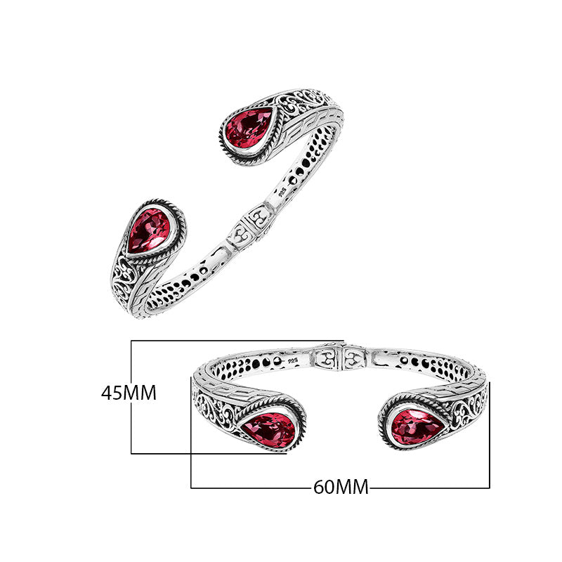 Sterling silver bangle with teardrop red garnet quartz stones, detailed Bali engraving, oxidized texture, and secure hinge lock crafted for wholesale jewelry collections.