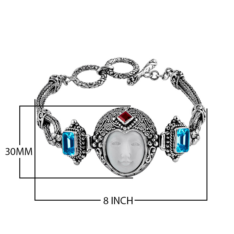 Sterling Silver bracelet featuring a carved bone face centerpiece, Red Garnet Quartz and Blue Topaz Quartz accents, ornate scrollwork, and a secure toggle lock for wholesale collections.