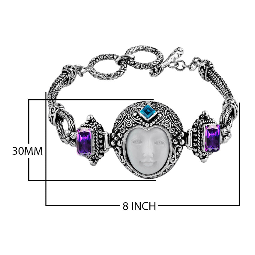 Sterling Silver bracelet featuring a carved bone face centerpiece, Garnet Quartz and Blue Topaz Quartz stones, detailed scroll panels, and a secure toggle lock for wholesale assortments.