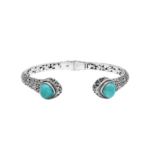 Wholesale sterling silver bangle featuring Larimar double-end stones, ornate Balinese scroll engravings, and a secure hinge lock for artisan-quality jewelry collections.