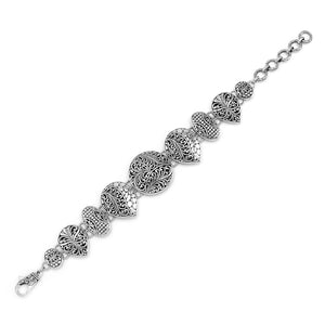 Wholesale sterling silver link bracelet featuring multiple carved Balinese motif shapes, intricate scroll engravings, and a secure lobster lock for premium artisan jewelry assortments.
