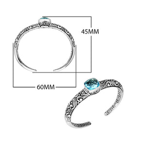 Wholesale sterling silver open bangle with a cushion-cut Blue Topaz Quartz centerpiece, intricate Balinese scroll engravings, and a secure hinge lock for artisan jewelry assortments.