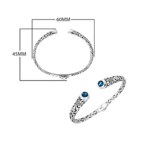 Wholesale sterling silver Bali engraved hinge cuff bracelet featuring sparkling blue topaz quartz ends and polished–oxidized detailing, crafted for premium artistic wholesale jewelry assortments and elevated inventory selections.