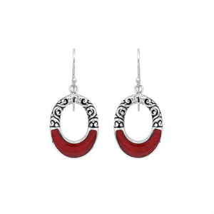 Sterling silver oval drop earrings featuring rich Red Coral inlay, open center design, sculpted scroll motifs, oxidized detailing, polished borders, and French ear wires.