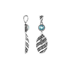 A wholesale Silver Overlay Over Copper pendant featuring a sparkling blue topaz quartz stone, detailed Balinese spiral patterns, oxidized textures, and polished highlights ideal for bulk jewelry purchasing.