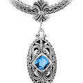 Sterling Silver Ornate Oval Pendant Featuring Blue Topaz Quartz With Fleur-De-Lis Decorative Bail.