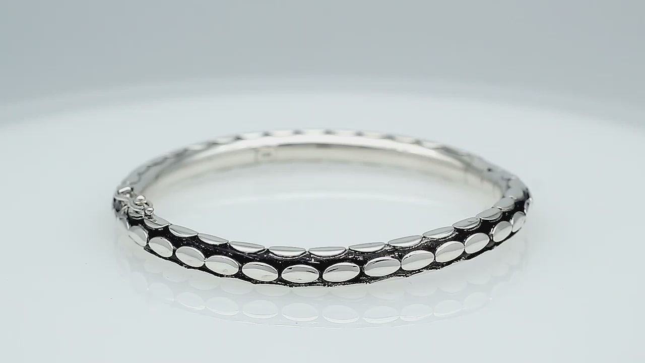 Sterling silver medium-size bangle featuring bold oval textured detailing, polished and oxidized finish, and secure hinge lock with safety latch for wholesale jewelry buyers.