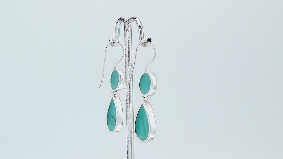 Sterling silver Turquoise Shell double drop earrings featuring circular upper settings, larger teardrop dangles, vibrant turquoise blue surfaces with dark veining, polished silver bezels, and curved fishhook earwires, shown in front and side views.