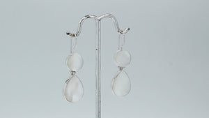 Sterling silver Mother Of Pearl dangle earrings featuring round and teardrop shell elements, polished bezel settings, articulated construction, and elegant elongated ear wires.