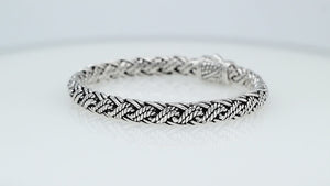 Sterling silver twisted rope chain bracelet featuring wrapped textured links, deep oxidized accents, polished detailing, and an engraved decorative push clasp.