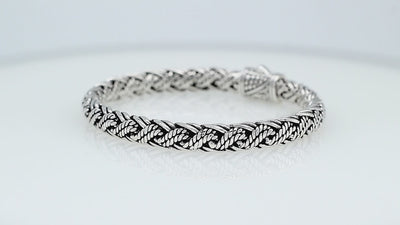 Sterling silver twisted rope chain bracelet featuring wrapped textured links, deep oxidized accents, polished detailing, and an engraved decorative push clasp.