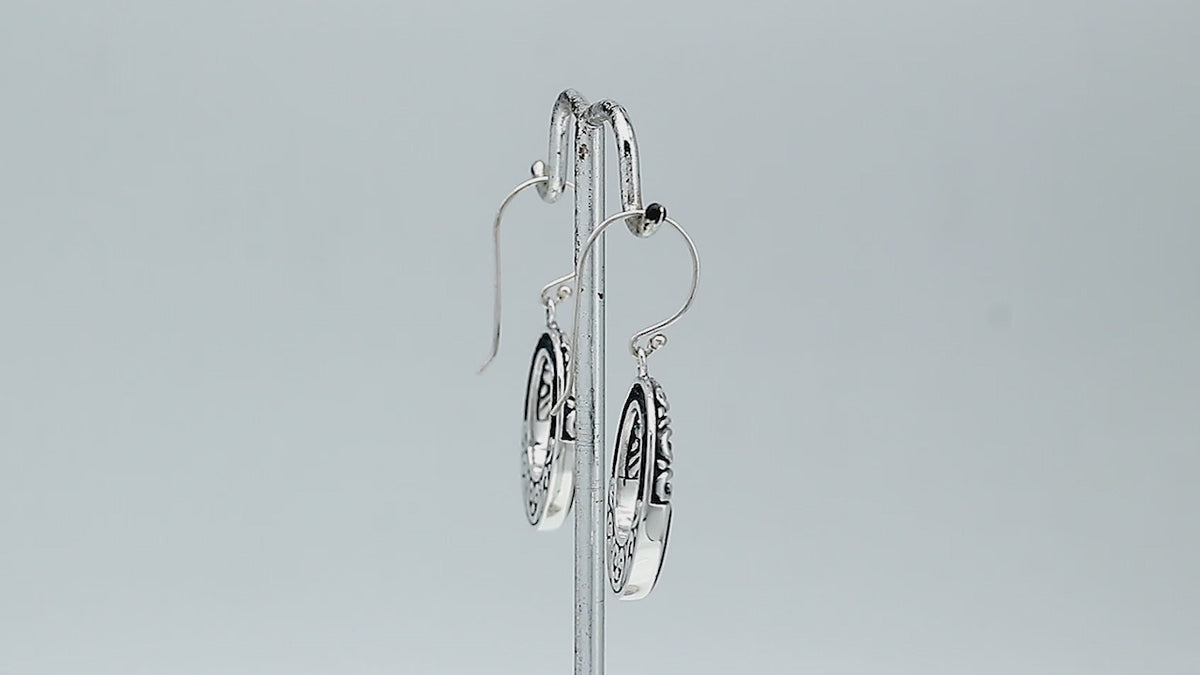 Sterling silver oval drop earrings featuring glossy Black Shell inlay, open center silhouette, sculpted scroll motifs, oxidized detailing, polished borders, and French ear wires.