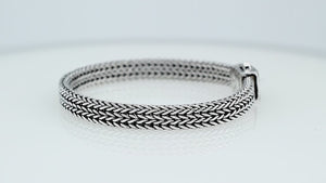 Sterling silver flat multi-strand woven braided chain bracelet featuring tightly interlaced silver links, oxidized detailing, and a decorative geometric push clasp, displayed from two angles.