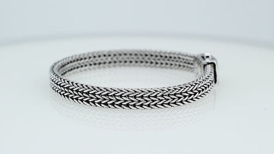 Sterling silver flat multi-strand woven braided chain bracelet featuring tightly interlaced silver links, oxidized detailing, and a decorative geometric push clasp, displayed from two angles.