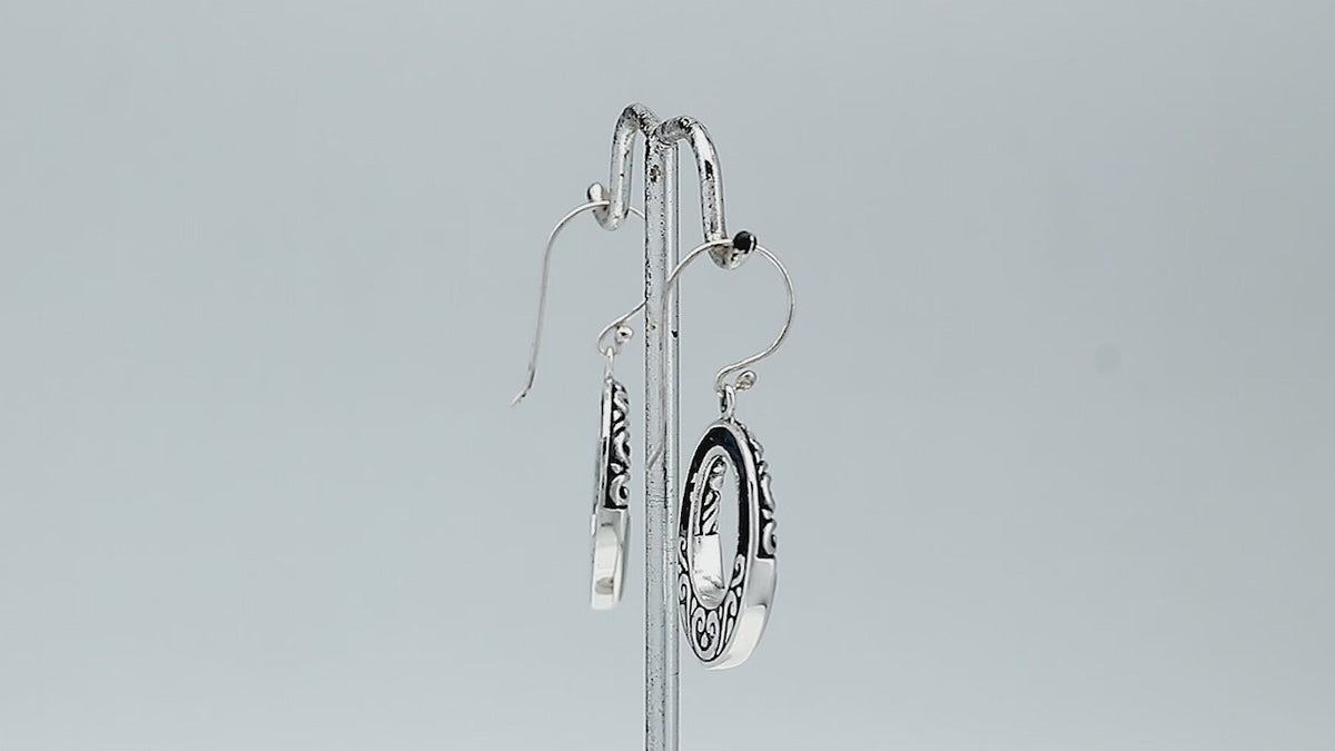 Sterling silver oval drop earrings featuring luminous Mother Of Pearl inlay, open center silhouette, decorative scrollwork, oxidized detailing, polished borders, and French ear wires.