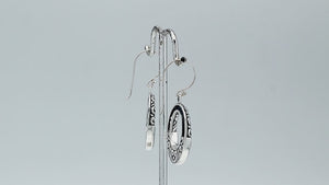 Sterling silver oval drop earrings featuring luminous Mother Of Pearl inlay, open center silhouette, decorative scrollwork, oxidized detailing, polished borders, and French ear wires.