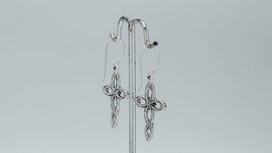 Sterling silver cross drop earrings featuring open oval sections, sculpted floral motifs, oxidized detailing, polished raised accents, and classic French ear wires.