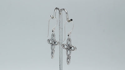 Sterling silver cross drop earrings featuring open oval sections, sculpted floral motifs, oxidized detailing, polished raised accents, and classic French ear wires.