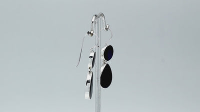 Sterling silver Black Shell dangle earrings featuring glossy round and teardrop elements, polished bezel settings, articulated double-drop construction, and elongated silver ear wires.