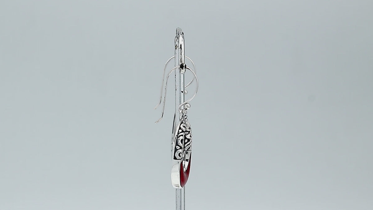 Sterling silver oval drop earrings featuring rich Red Coral inlay, open center design, sculpted scroll motifs, oxidized detailing, polished borders, and French ear wires.