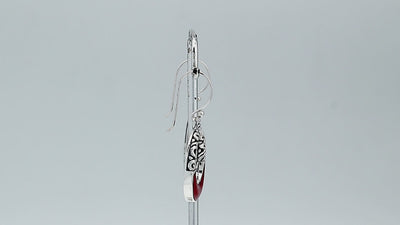 Sterling silver oval drop earrings featuring rich Red Coral inlay, open center design, sculpted scroll motifs, oxidized detailing, polished borders, and French ear wires.