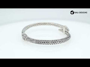 Wholesale sterling silver woven chain bangle featuring a sculpted nail-head design, intricate Balinese engravings, and a secure hinge lock for premium artisan jewelry assortments.