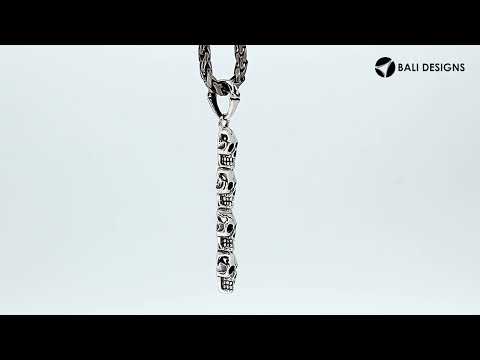 Sterling silver vertical skull pendant with carved detailing and polished finish.